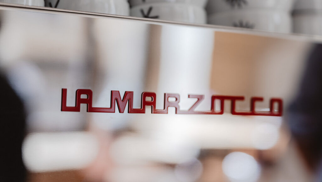 Efektivita pri zariaďovaní kaviarne: detail loga La Marzocco na profesionálnom kávovare.